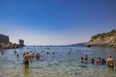15 Ağustos 2023 - Santa Cesarea Terme, Salento, Puglia, İtalya. Porto Miggiano 'nun inanılmaz körfezi. Turistlerle, banyolarla ve teknelerle dolu, harika denizin tadını çıkarıyorlar, berrak, mavi ve turkuaz..