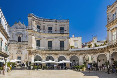 18 Ağustos 2023 - Martina Franca, Taranto, Puglia, İtalya. Barok mimarisi olan bir köy. Güzel Piazza Plebiscito, karakteristik girişi ile, turistlerle dolu. Yazın güneşli bir gün.