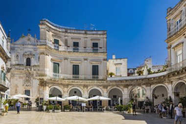 18 Ağustos 2023 - Martina Franca, Taranto, Puglia, İtalya. Barok mimarisi olan bir köy. Güzel Piazza Plebiscito, karakteristik girişi ile, turistlerle dolu. Yazın güneşli bir gün.
