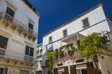 Martina Franca, Taranto, Puglia, İtalya. Barok mimarisi olan bir köy. Şehrin dar sokakları ve karakteristik balkonları olan binalar. Yazın güneşli bir günde mavi gökyüzü.