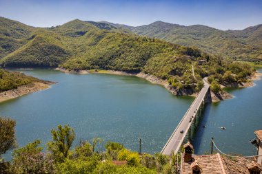 Turano Gölü manzaralı, İtalya 'nın Castel di Tora, Rieti, Lazio köyünden. Yeşil dağlarla çevrili, gölü geçen köprü. Yazın mavi gökyüzü.