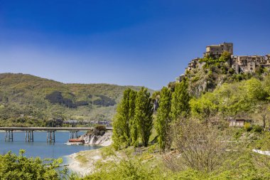 Turano Gölü manzaralı, İtalya 'nın Castel di Tora, Rieti, Lazio köyünden. Yeşil dağlarla çevrili, gölü geçen köprü. Yazın mavi gökyüzü.