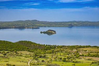 İtalya 'nın Viterbo kentindeki Montefiascone antik ortaçağ köyünün panoramik terasında görülen Bolsena Gölü' nün büyüleyici panoraması. Bir yaz akşamında ufukta sis var..