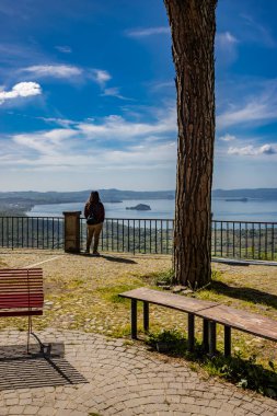 İtalya 'nın Viterbo kentindeki Montefiascone antik ortaçağ köyünün panoramik terasında görülen Bolsena Gölü' nün büyüleyici panoraması. Bazı turistler yaz akşamları manzaranın keyfini çıkarırlar..