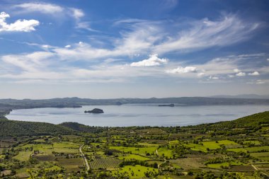 The enchanting panorama of Lake Bolsena, seen from the panoramic terrace of the ancient medieval village of Montefiascone, Viterbo, Italy. Mist on the horizon on a summer evening. clipart