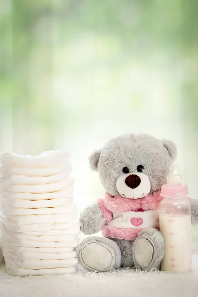 stack of diapers with soft teddy bear on table, hygiene concept