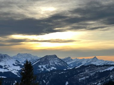 Obertoggenburg bölgesinde ve İsviçre Prealps, Urnaesch 'te (ya da Urnasch) kış bulutlarının ardında büyülü günbatımı ve utangaç güneş - Appenzell Innerrhoden Kantonu, İsviçre / Schweiz
