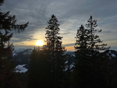 Obertoggenburg bölgesinde ve İsviçre Prealps, Urnaesch 'te (ya da Urnasch) kış bulutlarının ardında büyülü günbatımı ve utangaç güneş - Appenzell Innerrhoden Kantonu, İsviçre / Schweiz