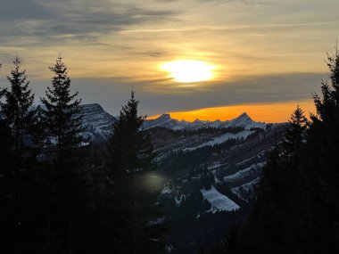 Obertoggenburg bölgesinde ve İsviçre Prealps, Urnaesch 'te (ya da Urnasch) kış bulutlarının ardında büyülü günbatımı ve utangaç güneş - Appenzell Innerrhoden Kantonu, İsviçre / Schweiz