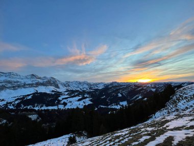 Obertoggenburg bölgesinde ve İsviçre Prealps, Urnaesch 'te (ya da Urnasch) kış bulutlarının ardında büyülü günbatımı ve utangaç güneş - Appenzell Innerrhoden Kantonu, İsviçre / Schweiz