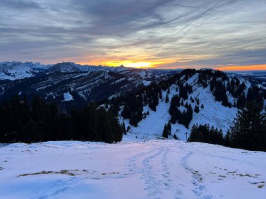 Obertoggenburg bölgesinde ve İsviçre Prealps, Urnaesch 'te (ya da Urnasch) kış bulutlarının ardında büyülü günbatımı ve utangaç güneş - Appenzell Innerrhoden Kantonu, İsviçre / Schweiz