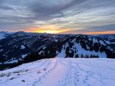 Obertoggenburg bölgesinde ve İsviçre Prealps, Urnaesch 'te (ya da Urnasch) kış bulutlarının ardında büyülü günbatımı ve utangaç güneş - Appenzell Innerrhoden Kantonu, İsviçre / Schweiz
