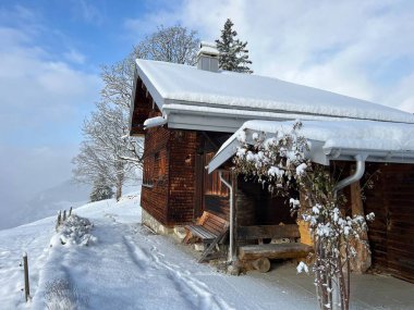 Indigenous alpine huts and wooden cattle stables in the Swiss Alps covered with fresh first snow over the Lake Walen or Lake Walenstadt (Walensee), Amden - Canton of St. Gallen, Switzerland / Schweiz
