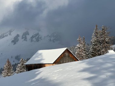 Indigenous alpine huts and wooden cattle stables in the Swiss Alps covered with fresh first snow over the Lake Walen or Lake Walenstadt (Walensee), Amden - Canton of St. Gallen, Switzerland / Schweiz