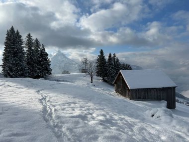 Indigenous alpine huts and wooden cattle stables in the Swiss Alps covered with fresh first snow over the Lake Walen or Lake Walenstadt (Walensee), Amden - Canton of St. Gallen, Switzerland / Schweiz