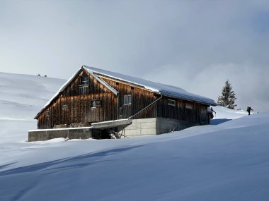 Indigenous alpine huts and wooden cattle stables in the Swiss Alps covered with fresh first snow over the Lake Walen or Lake Walenstadt (Walensee), Amden - Canton of St. Gallen, Switzerland / Schweiz