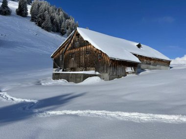 Indigenous alpine huts and wooden cattle stables in the Swiss Alps covered with fresh first snow over the Lake Walen or Lake Walenstadt (Walensee), Amden - Canton of St. Gallen, Switzerland / Schweiz