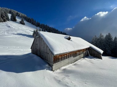 Indigenous alpine huts and wooden cattle stables in the Swiss Alps covered with fresh first snow over the Lake Walen or Lake Walenstadt (Walensee), Amden - Canton of St. Gallen, Switzerland / Schweiz