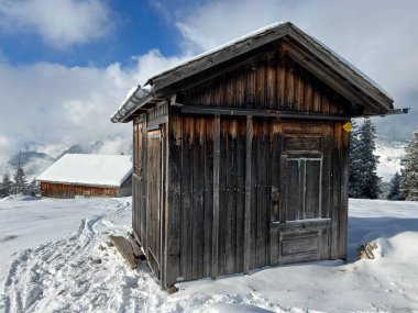 Indigenous alpine huts and wooden cattle stables in the Swiss Alps covered with fresh first snow over the Lake Walen or Lake Walenstadt (Walensee), Amden - Canton of St. Gallen, Switzerland / Schweiz
