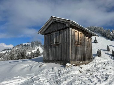 Indigenous alpine huts and wooden cattle stables in the Swiss Alps covered with fresh first snow over the Lake Walen or Lake Walenstadt (Walensee), Amden - Canton of St. Gallen, Switzerland / Schweiz
