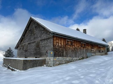 Indigenous alpine huts and wooden cattle stables in the Swiss Alps covered with fresh first snow over the Lake Walen or Lake Walenstadt (Walensee), Amden - Canton of St. Gallen, Switzerland / Schweiz
