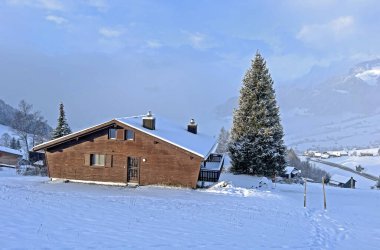 Old traditional swiss rural architecture and alpine livestock farms in the winter ambience over the Lake Walen or Lake Walenstadt (Walensee) and in the Swiss Alps, Amden - Canton of St. Gallen, Switzerland / Schweiz