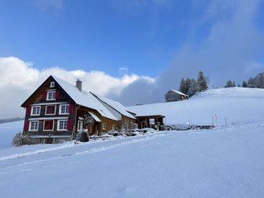 Old traditional swiss rural architecture and alpine livestock farms in the winter ambience over the Lake Walen or Lake Walenstadt (Walensee) and in the Swiss Alps, Amden - Canton of St. Gallen, Switzerland / Schweiz