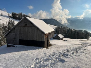 Indigenous alpine huts and wooden cattle stables in the Swiss Alps covered with fresh first snow over the Lake Walen or Lake Walenstadt (Walensee), Amden - Canton of St. Gallen, Switzerland / Schweiz