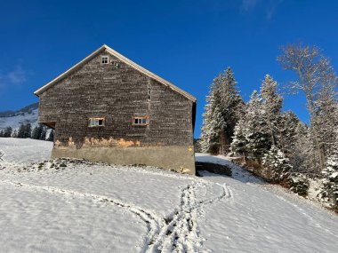 Indigenous alpine huts and wooden cattle stables in the Swiss Alps covered with fresh first snow over the Lake Walen or Lake Walenstadt (Walensee), Amden - Canton of St. Gallen, Switzerland / Schweiz