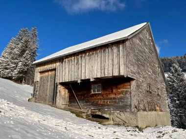 Indigenous alpine huts and wooden cattle stables in the Swiss Alps covered with fresh first snow over the Lake Walen or Lake Walenstadt (Walensee), Amden - Canton of St. Gallen, Switzerland / Schweiz