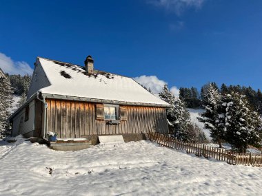 Indigenous alpine huts and wooden cattle stables in the Swiss Alps covered with fresh first snow over the Lake Walen or Lake Walenstadt (Walensee), Amden - Canton of St. Gallen, Switzerland / Schweiz