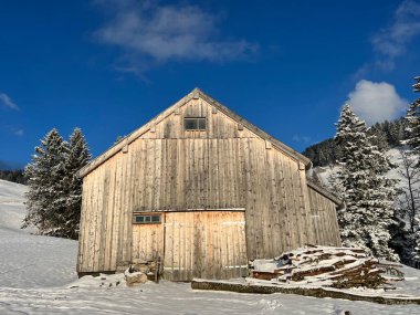 Indigenous alpine huts and wooden cattle stables in the Swiss Alps covered with fresh first snow over the Lake Walen or Lake Walenstadt (Walensee), Amden - Canton of St. Gallen, Switzerland / Schweiz