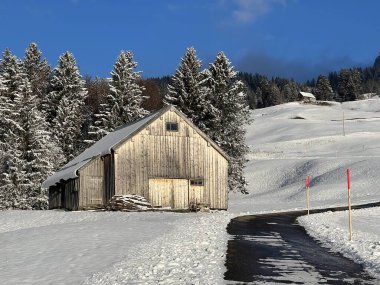 Indigenous alpine huts and wooden cattle stables in the Swiss Alps covered with fresh first snow over the Lake Walen or Lake Walenstadt (Walensee), Amden - Canton of St. Gallen, Switzerland / Schweiz