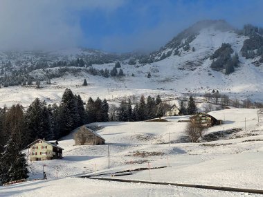 Indigenous alpine huts and wooden cattle stables in the Swiss Alps covered with fresh first snow over the Lake Walen or Lake Walenstadt (Walensee), Amden - Canton of St. Gallen, Switzerland / Schweiz