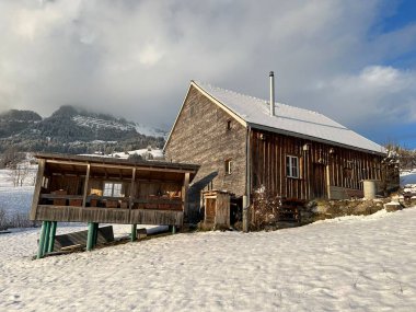 Indigenous alpine huts and wooden cattle stables in the Swiss Alps covered with fresh first snow over the Lake Walen or Lake Walenstadt (Walensee), Amden - Canton of St. Gallen, Switzerland / Schweiz