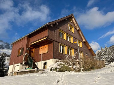 Old traditional swiss rural architecture and alpine livestock farms in the winter ambience over the Lake Walen or Lake Walenstadt (Walensee) and in the Swiss Alps, Amden - Canton of St. Gallen, Switzerland / Schweiz
