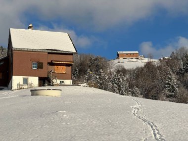 Old traditional swiss rural architecture and alpine livestock farms in the winter ambience over the Lake Walen or Lake Walenstadt (Walensee) and in the Swiss Alps, Amden - Canton of St. Gallen, Switzerland / Schweiz