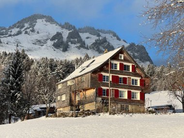 Old traditional swiss rural architecture and alpine livestock farms in the winter ambience over the Lake Walen or Lake Walenstadt (Walensee) and in the Swiss Alps, Amden - Canton of St. Gallen, Switzerland / Schweiz