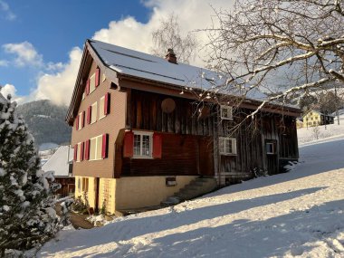 Old traditional swiss rural architecture and alpine livestock farms in the winter ambience over the Lake Walen or Lake Walenstadt (Walensee) and in the Swiss Alps, Amden - Canton of St. Gallen, Switzerland / Schweiz