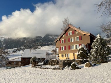 Old traditional swiss rural architecture and alpine livestock farms in the winter ambience over the Lake Walen or Lake Walenstadt (Walensee) and in the Swiss Alps, Amden - Canton of St. Gallen, Switzerland / Schweiz