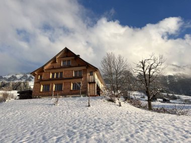 Old traditional swiss rural architecture and alpine livestock farms in the winter ambience over the Lake Walen or Lake Walenstadt (Walensee) and in the Swiss Alps, Amden - Canton of St. Gallen, Switzerland / Schweiz