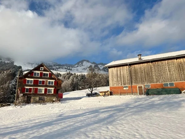 Old traditional swiss rural architecture and alpine livestock farms in the winter ambience over the Lake Walen or Lake Walenstadt (Walensee) and in the Swiss Alps, Amden - Canton of St. Gallen, Switzerland / Schweiz