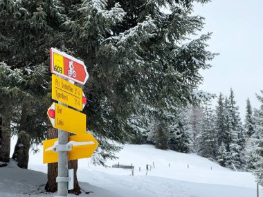 Hiking markings and orientation signs with signposts for navigating in the idyllic winter ambience above the tourist resorts of Valbella and Lenzerheide in the Swiss Alps - Canton of Grisons, Switzerland / Schweiz