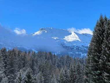 The last rays of the late afternoon sun on the alpine winter snowy peaks above the tourist resorts of Valbella and Lenzerheide in the Swiss Alps - Canton of Grisons, Switzerland (Schweiz)