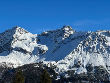 Beautiful sunlit and snow-capped alpine peaks above the Swiss tourist sports-recreational winter resort of Arosa - Canton of Grisons, Switzerland (Schweiz)
