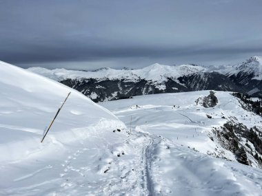 İsviçre Alpleri 'nin taze dağlık kar örtüsünde ve İsviçre' nin Grisonlar Kantonu, İsviçre 'nin turistik tatil beldesi Arosa' nın üzerinde harika kış yürüyüşü patikaları ve izler var.)