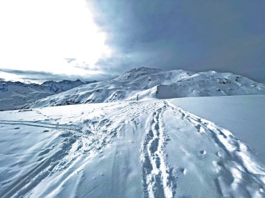 İsviçre Alpleri 'nin taze dağlık kar örtüsünde ve İsviçre' nin Grisonlar Kantonu, İsviçre 'nin turistik tatil beldesi Arosa' nın üzerinde harika kış yürüyüşü patikaları ve izler var.)