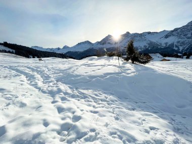 Sabahın erken saatlerinde, İsviçre 'nin ünlü kış beldesi Arosa' nın karlı dağlık tepelerinde yükselen güneş, İsviçre 'nin Grisonlar Kantonu (Schweiz)