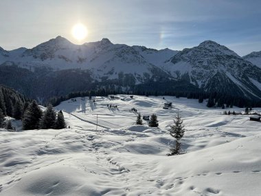 Sabahın erken saatlerinde, İsviçre 'nin ünlü kış beldesi Arosa' nın karlı dağlık tepelerinde yükselen güneş, İsviçre 'nin Grisonlar Kantonu (Schweiz)