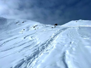 İsviçre Alpleri 'nin taze dağlık kar örtüsünde ve İsviçre' nin Grisonlar Kantonu, İsviçre 'nin turistik tatil beldesi Arosa' nın üzerinde harika kış yürüyüşü patikaları ve izler var.)